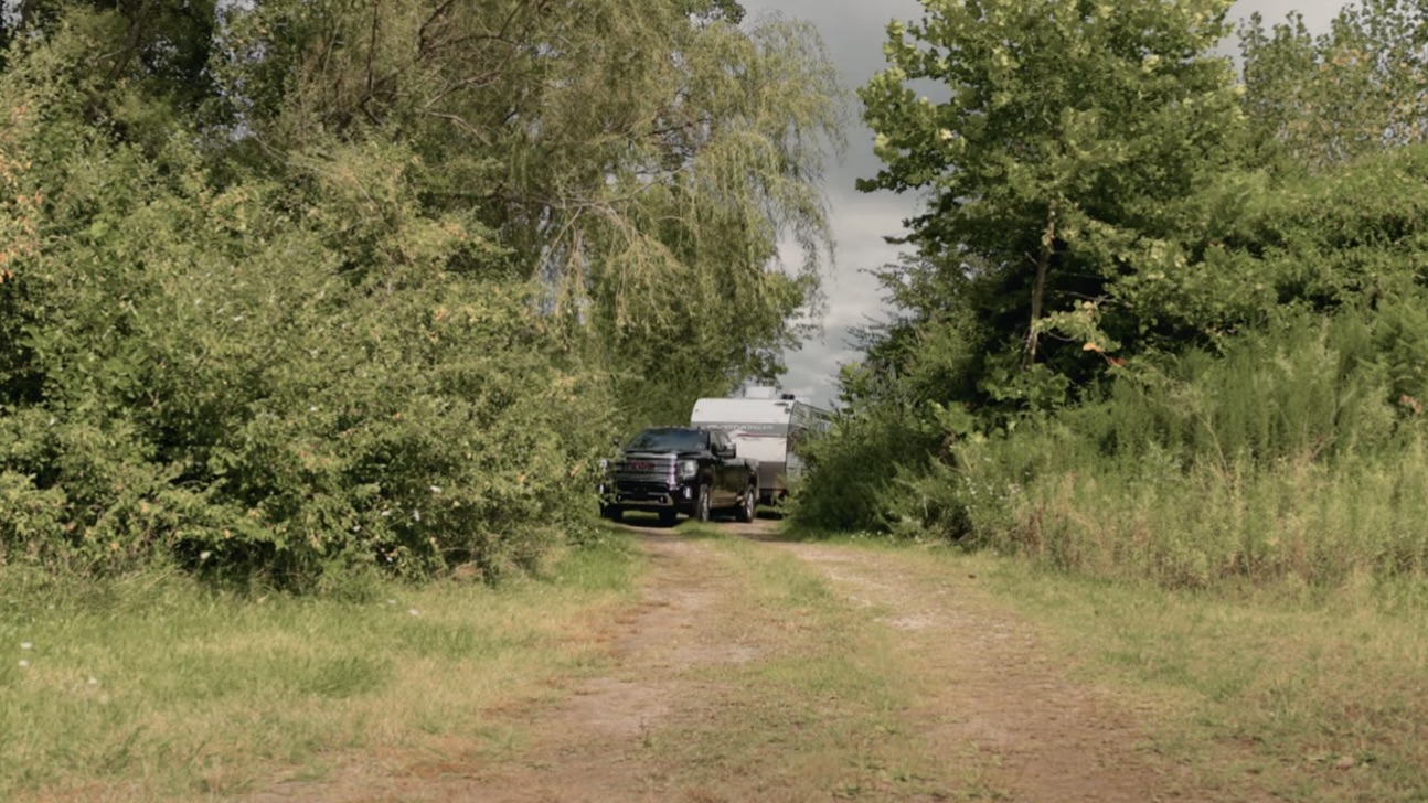 Un camion qui arrive sur un terrain de camping avec une roulotte.