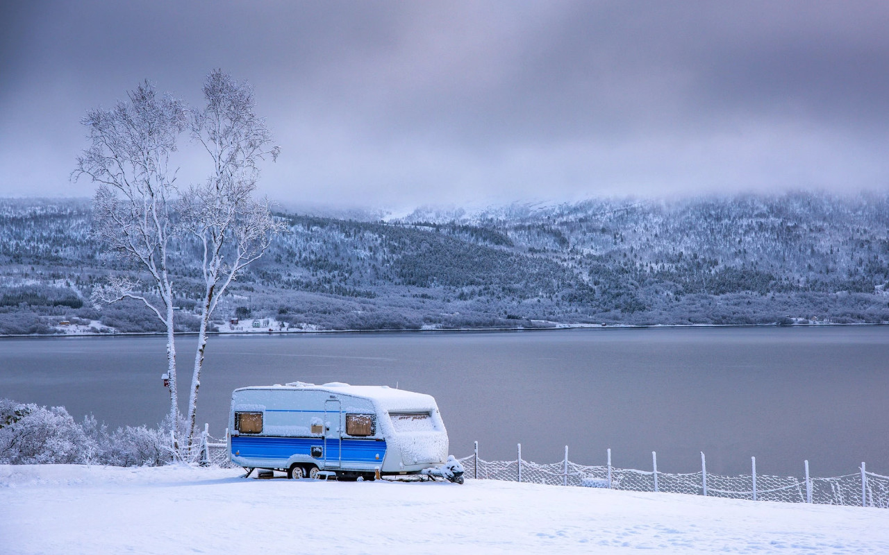 vue d'une roulotte sur un terrain enneigé près d'un lac en hiver