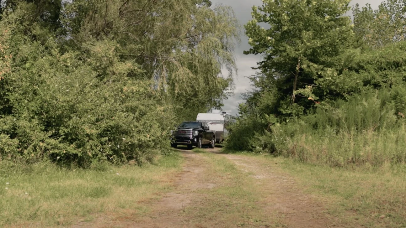 Un camion qui arrive sur un terrain de camping avec une roulotte.