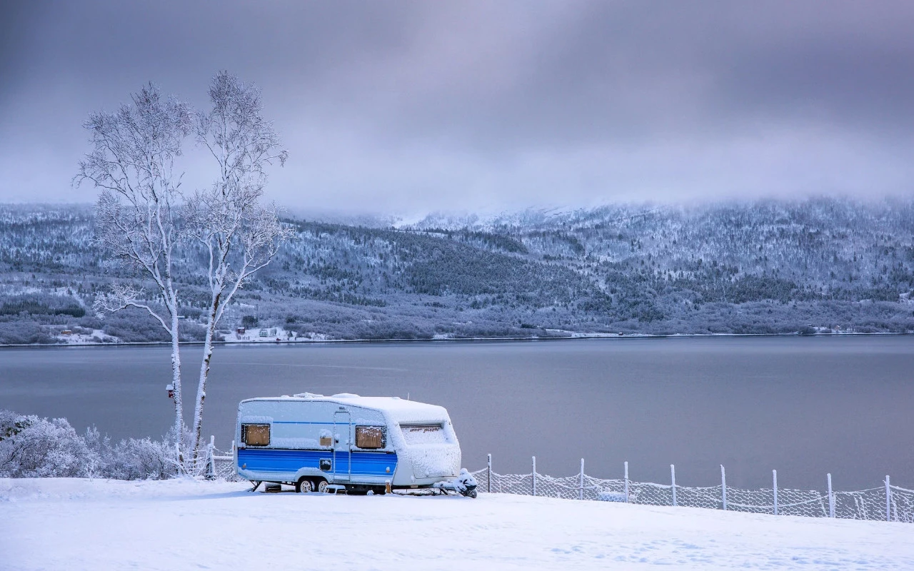 vue d'une roulotte sur un terrain enneigé près d'un lac en hiver